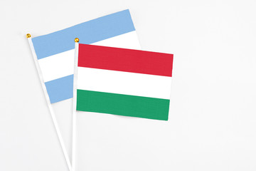 Hungary and Argentina stick flags on white background. High quality fabric, miniature national flag. Peaceful global concept.White floor for copy space.