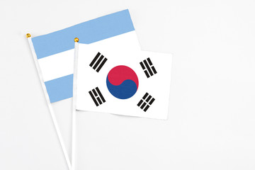 South Korea and Argentina stick flags on white background. High quality fabric, miniature national flag. Peaceful global concept.White floor for copy space.