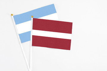 Latvia and Argentina stick flags on white background. High quality fabric, miniature national flag. Peaceful global concept.White floor for copy space.