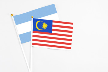 Malaysia and Argentina stick flags on white background. High quality fabric, miniature national flag. Peaceful global concept.White floor for copy space.