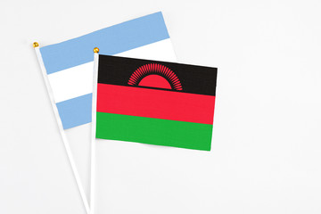 Malawi and Argentina stick flags on white background. High quality fabric, miniature national flag. Peaceful global concept.White floor for copy space.