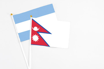 Nepal and Argentina stick flags on white background. High quality fabric, miniature national flag. Peaceful global concept.White floor for copy space.