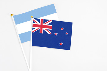Fototapeta premium New Zealand and Argentina stick flags on white background. High quality fabric, miniature national flag. Peaceful global concept.White floor for copy space.