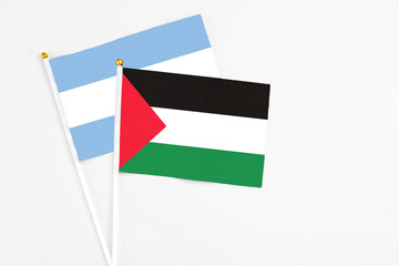 Palestine and Argentina stick flags on white background. High quality fabric, miniature national flag. Peaceful global concept.White floor for copy space.