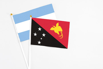Papua New Guinea and Argentina stick flags on white background. High quality fabric, miniature national flag. Peaceful global concept.White floor for copy space.