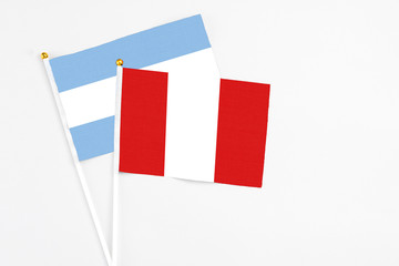 Peru and Argentina stick flags on white background. High quality fabric, miniature national flag. Peaceful global concept.White floor for copy space.