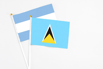 Saint Lucia and Argentina stick flags on white background. High quality fabric, miniature national flag. Peaceful global concept.White floor for copy space.