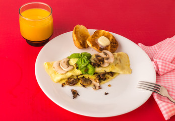 Mushroom Onion and cheese Omelet with buttered toast and orange juice on red background with copy space.