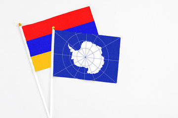 Antarctica and Armenia stick flags on white background. High quality fabric, miniature national flag. Peaceful global concept.White floor for copy space.