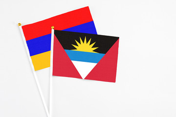 Antigua and Barbuda and Armenia stick flags on white background. High quality fabric, miniature national flag. Peaceful global concept.White floor for copy space.
