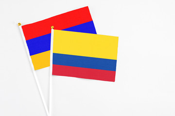 Colombia and Armenia stick flags on white background. High quality fabric, miniature national flag. Peaceful global concept.White floor for copy space.