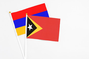 East Timor and Armenia stick flags on white background. High quality fabric, miniature national flag. Peaceful global concept.White floor for copy space.