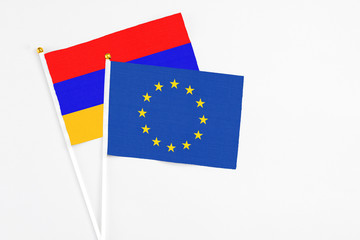 European Union and Armenia stick flags on white background. High quality fabric, miniature national flag. Peaceful global concept.White floor for copy space.