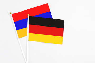 Germany and Armenia stick flags on white background. High quality fabric, miniature national flag. Peaceful global concept.White floor for copy space.