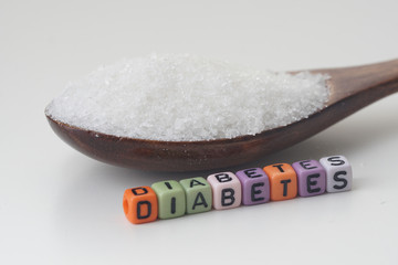 Health concept. Sugar in a wooden spoon with a DIABETES wording