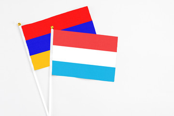 Luxembourg and Armenia stick flags on white background. High quality fabric, miniature national flag. Peaceful global concept.White floor for copy space.