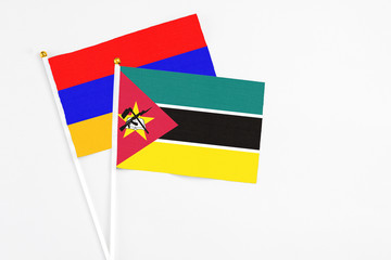 Mozambique and Armenia stick flags on white background. High quality fabric, miniature national flag. Peaceful global concept.White floor for copy space.