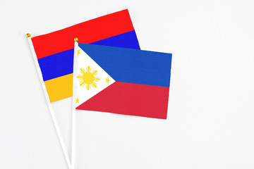 Philippines and Armenia stick flags on white background. High quality fabric, miniature national flag. Peaceful global concept.White floor for copy space.