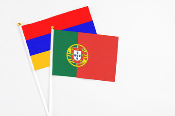 Portugal and Armenia stick flags on white background. High quality fabric, miniature national flag. Peaceful global concept.White floor for copy space.