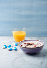 Bowl of granola with yogurt, nuts, raisins, cranberries and chia seeds. Blue dumbbells and sports supplements in background. Concept for a tasty and healthy meal. Stone - wooden background. 