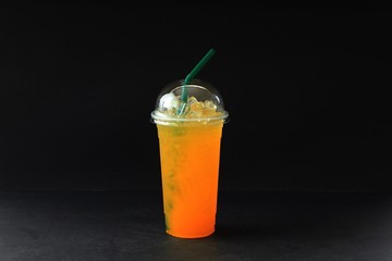 a glass of iced orange jucice on black background