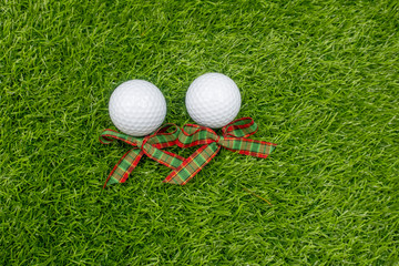 Golf ball with Christmas ribbon are on green grass