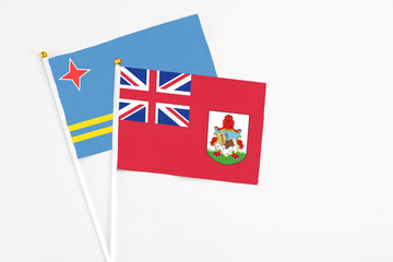 Fototapeta premium Bermuda and Aruba stick flags on white background. High quality fabric, miniature national flag. Peaceful global concept.White floor for copy space.