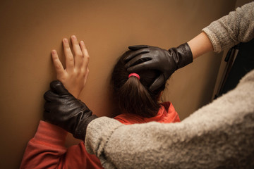 Woman in black leather gloves pressed girl's head against the wall