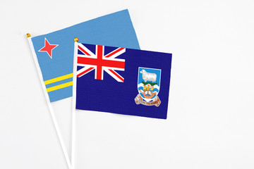 Fototapeta premium Falkland Islands and Aruba stick flags on white background. High quality fabric, miniature national flag. Peaceful global concept.White floor for copy space.