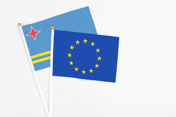 European Union and Aruba stick flags on white background. High quality fabric, miniature national flag. Peaceful global concept.White floor for copy space.
