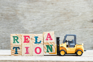 Toy forklift hold letter block a, n to complete word relation on wood background