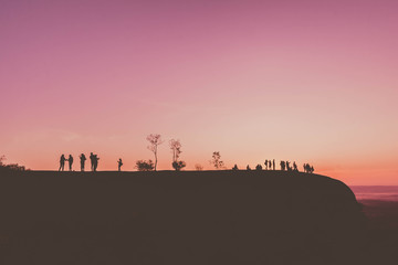 Silhouette picture of people on mountain peak rock at morning sunrise background. Landscape nature