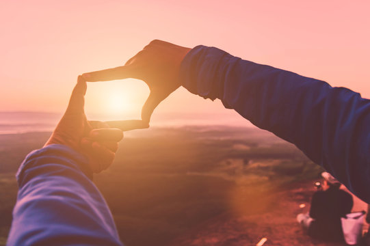 Wonderful mountain and sunrise natural background. Women taking picture with finger frame camera.