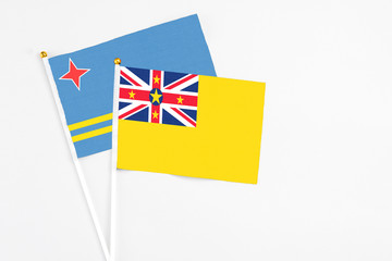 Fototapeta premium Niue and Aruba stick flags on white background. High quality fabric, miniature national flag. Peaceful global concept.White floor for copy space.