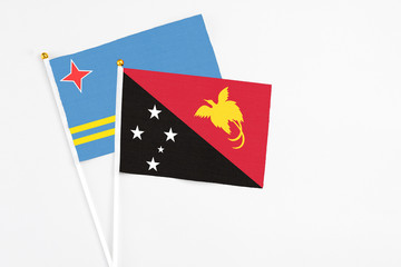 Papua New Guinea and Aruba stick flags on white background. High quality fabric, miniature national flag. Peaceful global concept.White floor for copy space.