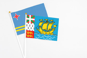 Saint Pierre And Miquelon and Aruba stick flags on white background. High quality fabric, miniature national flag. Peaceful global concept.White floor for copy space.