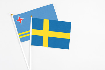 Sweden and Aruba stick flags on white background. High quality fabric, miniature national flag. Peaceful global concept.White floor for copy space.