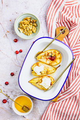 Sweet baked pears with honey, nuts, cranberries and cinnamon in enameled baking bowl on stone background. Top view. Flat lay