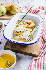 Sweet baked pears with honey, nuts, cranberries and cinnamon in enameled baking bowl on stone background. Top view. Flat lay