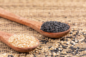 Wooden spoon full of both healthy sesame and black sesame seeds