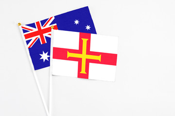 Fototapeta premium Guernsey and Australia stick flags on white background. High quality fabric, miniature national flag. Peaceful global concept.White floor for copy space.