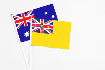 Fototapeta premium Niue and Australia stick flags on white background. High quality fabric, miniature national flag. Peaceful global concept.White floor for copy space.