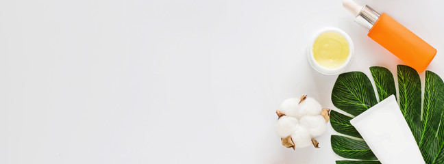 Flat lay with Natural organic cosmetics: serum, cream on white background with cotton flowers. Skincare, cosmetology, dermatology concept. Beauty certificate, blog style. Top view, mockup, overhead