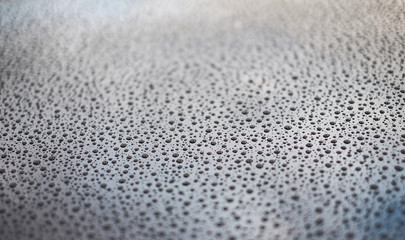 Drops of rain on graphite gray glossy surface.