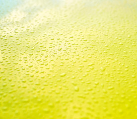 Fine droplets of water on a bright yellow glossy surface.