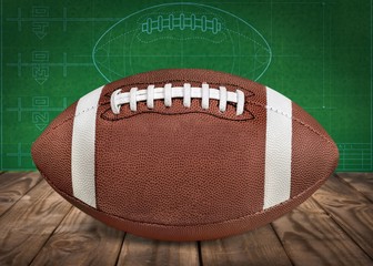American football ball on wooden table on green wall
