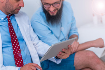 A doctor is talking to hipster patient in the office and explain's to him his diagnosis.