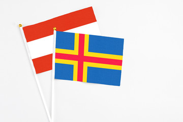 Aland Islands and Austria stick flags on white background. High quality fabric, miniature national flag. Peaceful global concept.White floor for copy space.