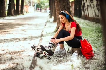 Sporty female putting on skates in city park