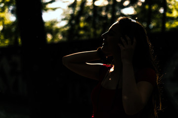 Happy young woman with headphones listening to music in city park